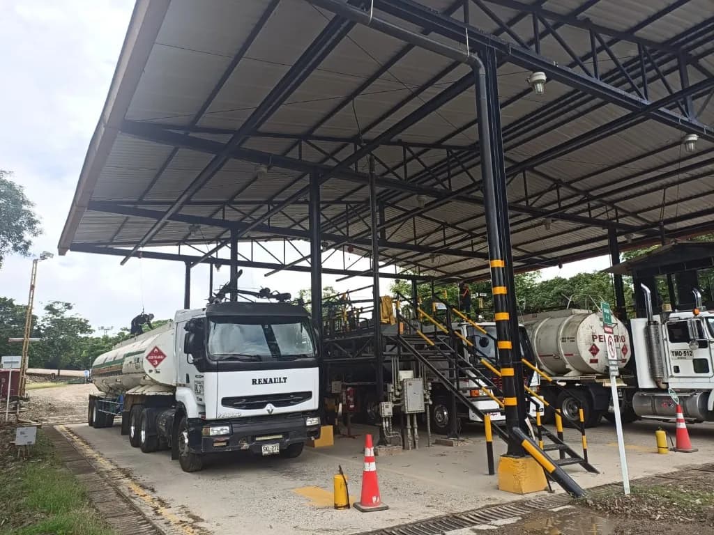 Estación de cargue con varios carrotanques, pasarela de acceso y señalización HSE en operación de hidrocarburos.